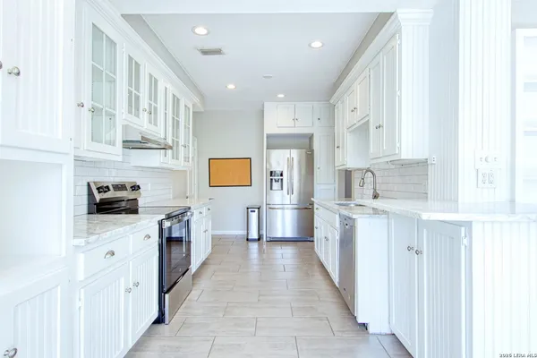 a kitchen with stainless steel appliances granite countertop white cabinets and a sink