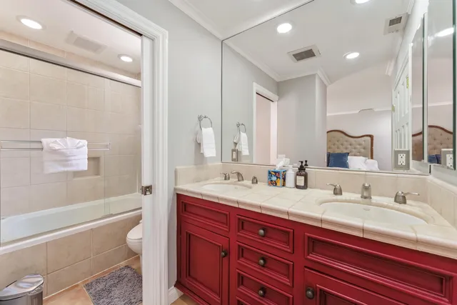 a bathroom with a granite countertop double vanity sink toilet mirror and bathtub