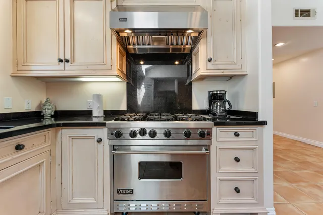 a stove top oven sitting inside of a kitchen and white cabinets