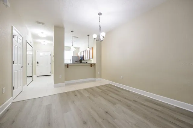 a view of a hallway with wooden floor and a kitchen