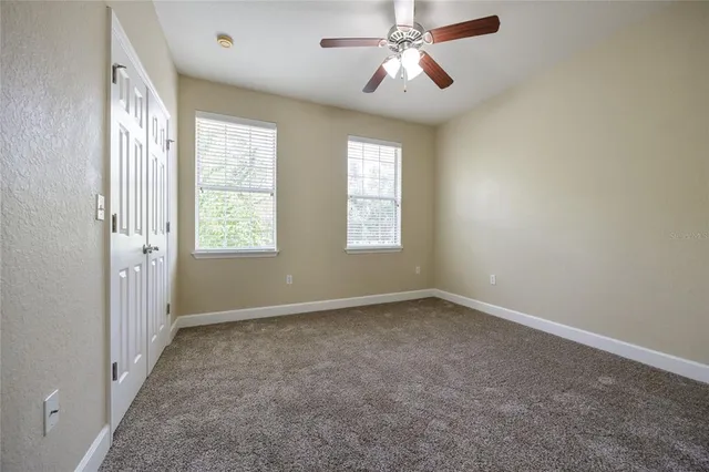 an empty room with windows and fan