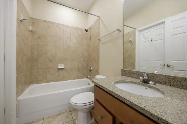 a bathroom with a granite countertop bathtub shower sink vanity mirror and toilet