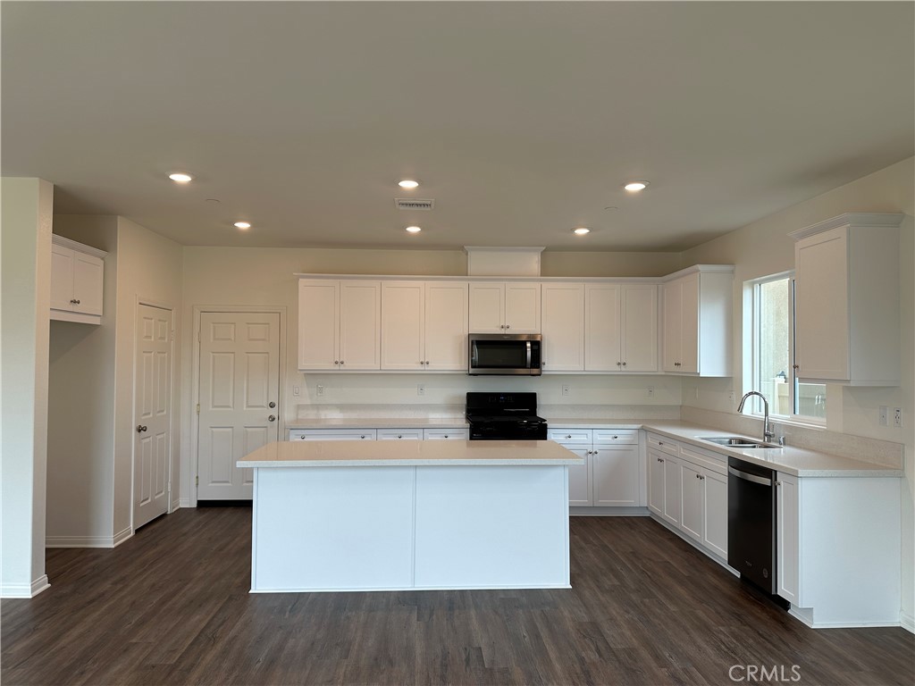 7560 Citrusmoon Court Riverside, CA 92507 - Photo 2 of 18 a kitchen with stainless steel appliances wooden floors and white cabinets