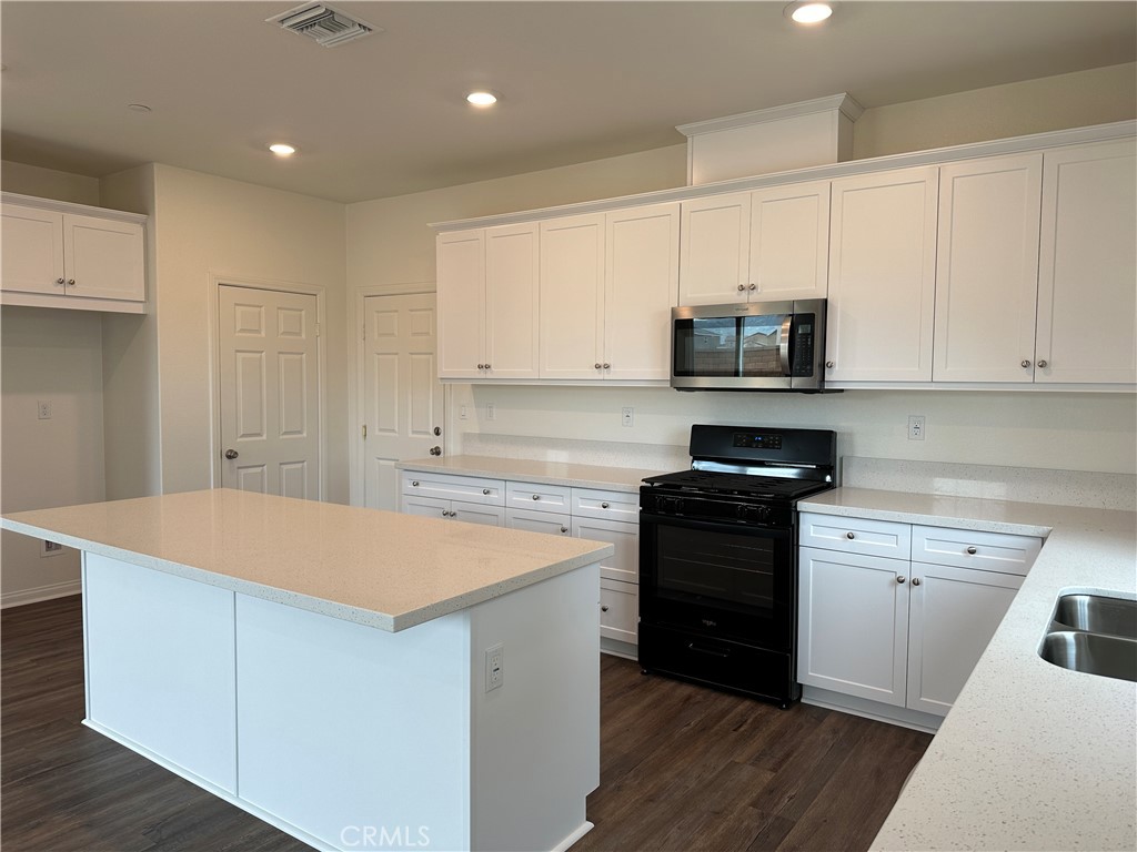 7560 Citrusmoon Court Riverside, CA 92507 - Photo 4 of 18 a kitchen with stainless steel appliances a stove a sink and white cabinets