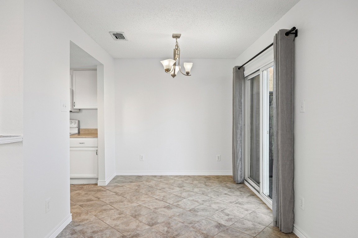 2630 Alcott Lane, Unit A Austin, TX 78748 - Photo 11 of 32 Unfurnished dining area with a chandelier, a textured ceiling, and light tile patterned flooring