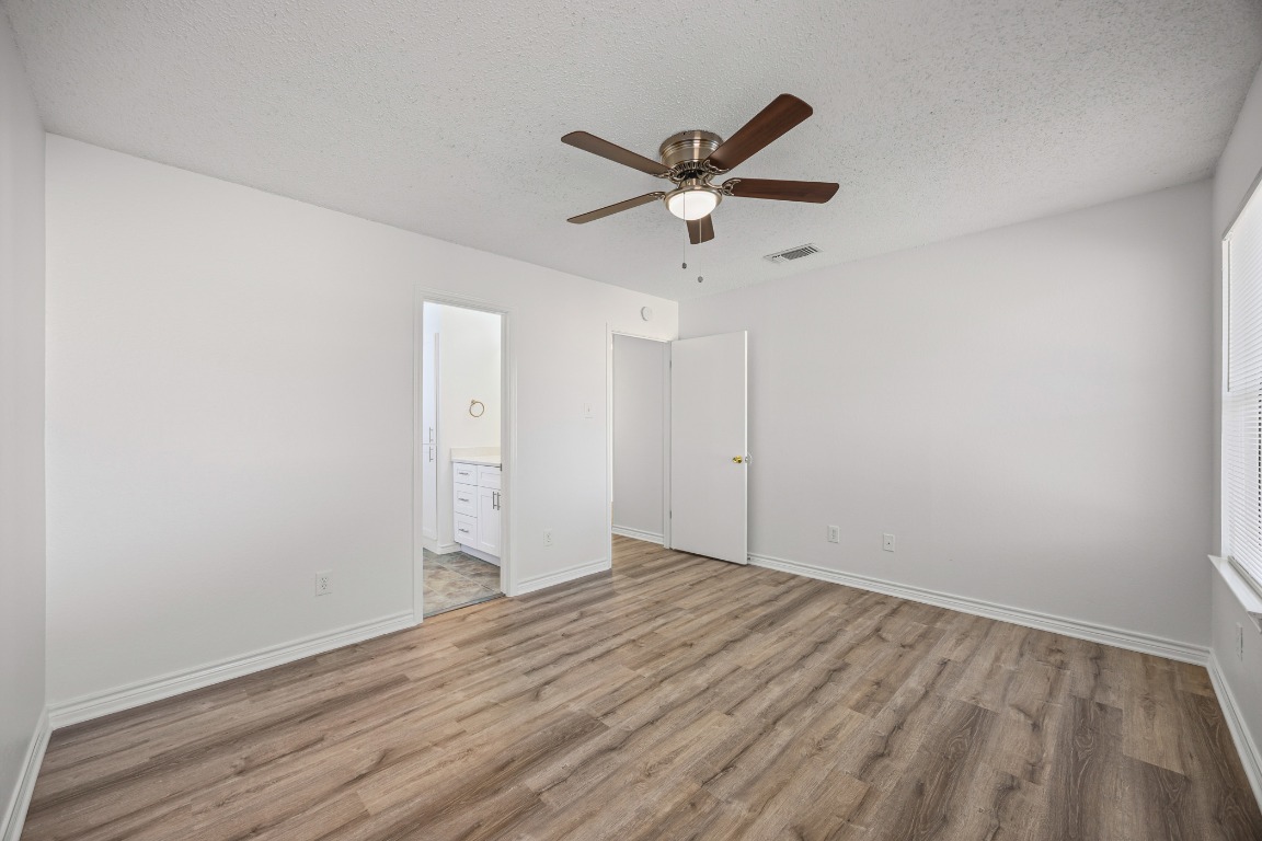 2630 Alcott Lane, Unit A Austin, TX 78748 - Photo 18 of 32 Unfurnished bedroom featuring a textured ceiling, a ceiling fan, light wood-style flooring, and connected bathroom