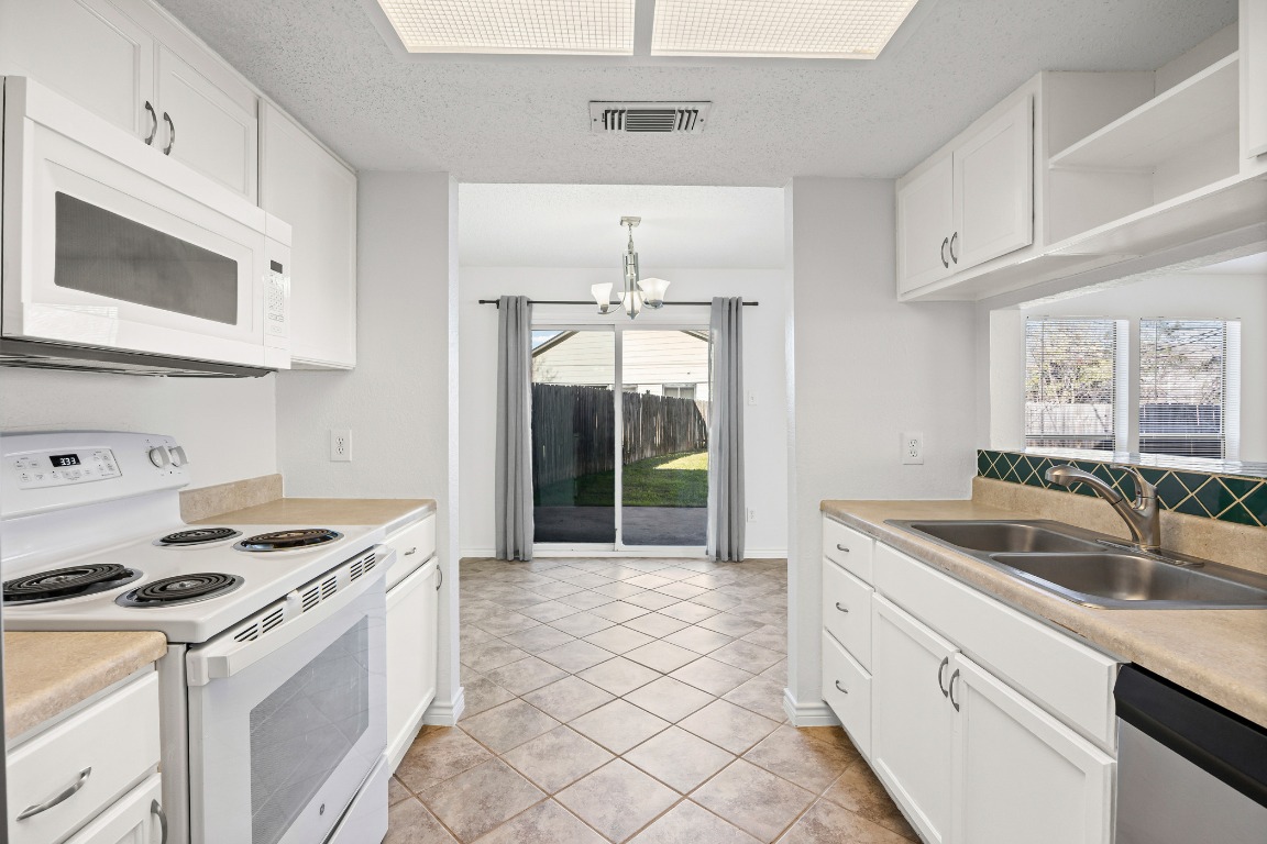 2630 Alcott Lane, Unit A Austin, TX 78748 - Photo 3 of 32 Kitchen with white appliances, a chandelier, light countertops, white cabinetry, and open shelves