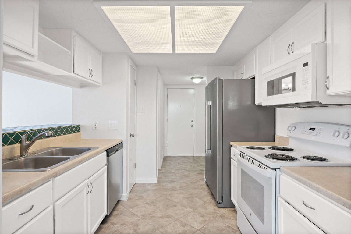 2630 Alcott Lane, Unit A Austin, TX 78748 - Photo 4 of 32 Kitchen with white appliances, white cabinets, light countertops, and decorative backsplash