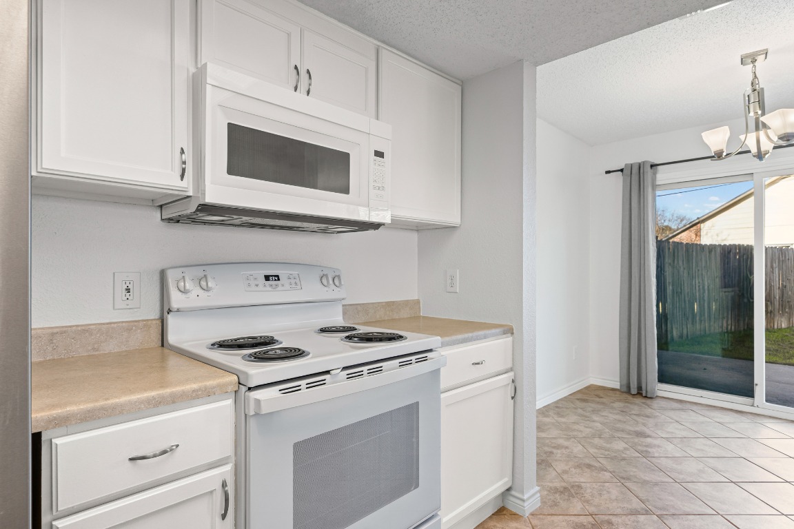 2630 Alcott Lane, Unit A Austin, TX 78748 - Photo 5 of 32 Kitchen with white appliances, a chandelier, white cabinetry, light countertops, and a textured ceiling