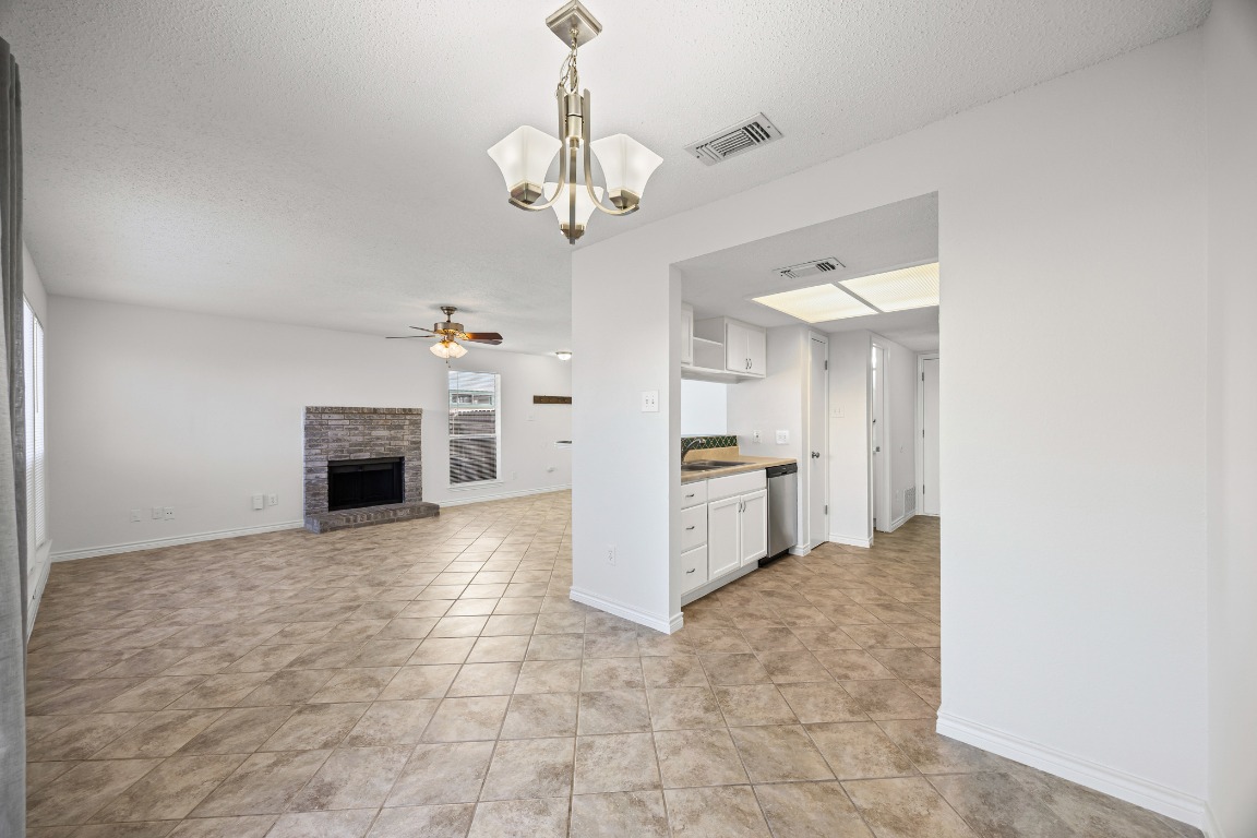 2630 Alcott Lane, Unit A Austin, TX 78748 - Photo 6 of 32 Kitchen with a chandelier, white cabinets, a brick fireplace, hanging light fixtures, and a textured ceiling