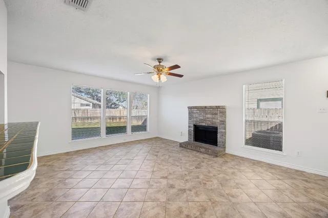 an empty room with a fireplace and a ceiling fan