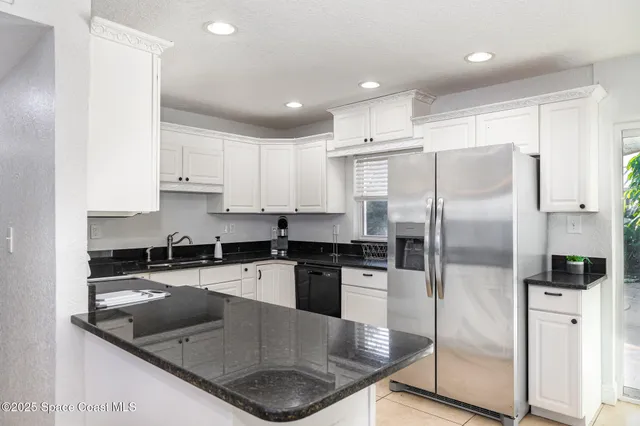 a kitchen with stainless steel appliances granite countertop a refrigerator a stove and white cabinets