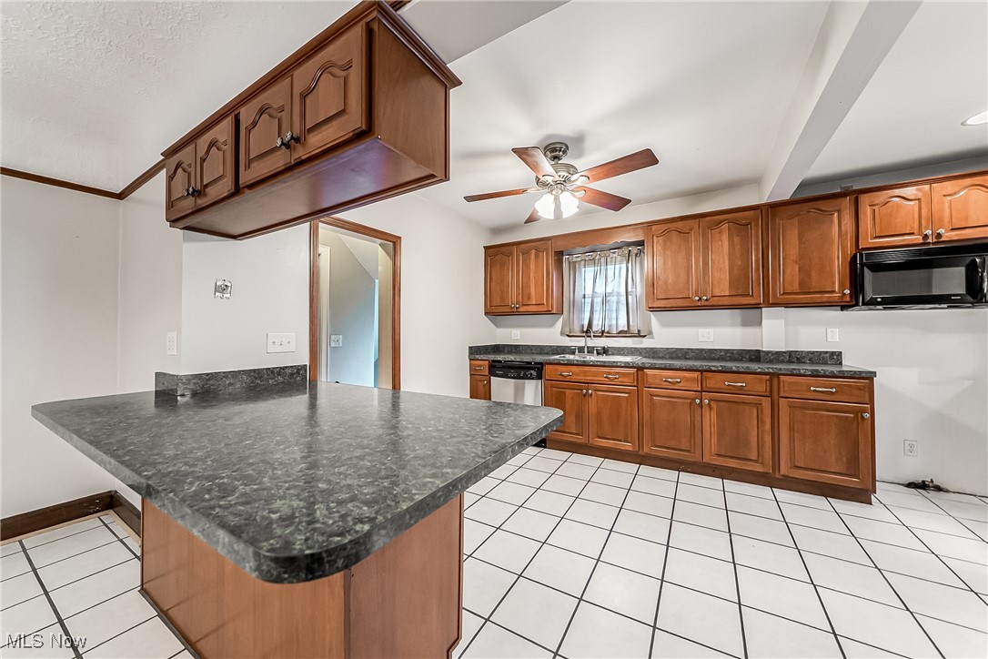 1271 Winston Road Cleveland, OH 44121 - Photo 12 of 43 Kitchen featuring black microwave, a peninsula, ceiling fan, light tile patterned floors, and brown cabinetry