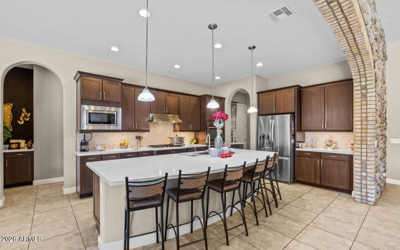 2915 East Constance Way Phoenix, AZ 85042 - Photo 18 of 47 a kitchen with stainless steel appliances kitchen island granite countertop a refrigerator a stove a sink a dining table and chairs with wooden floor