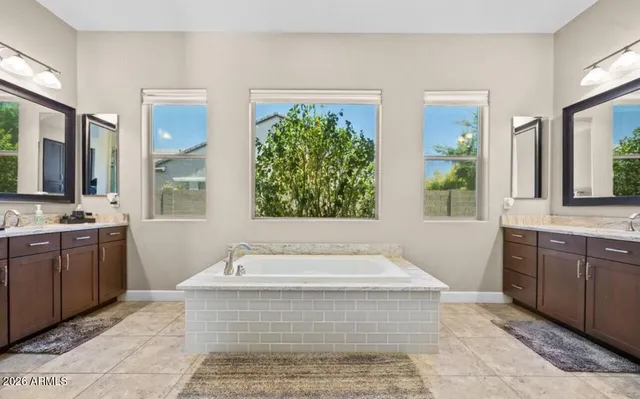a spacious bathroom with a tub sink and mirror