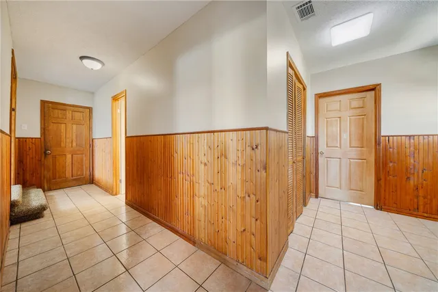 an empty room with a chandelier fan and windows