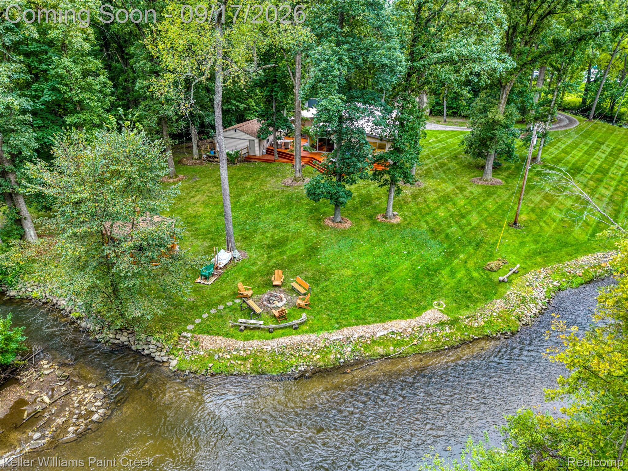 4535 Orion Road Rochester, MI 48306 - Photo 1 of 67 Waterfront property featuring a stone-lined creek bank, expansive lawn, mature trees, and a ground-level deck
