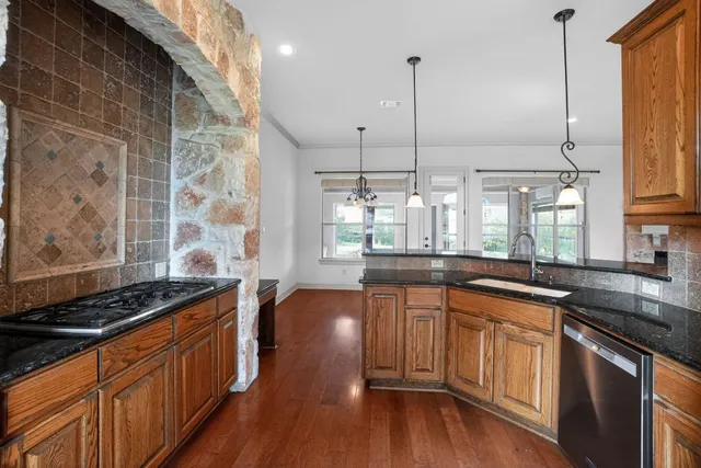a kitchen with stainless steel appliances granite countertop a stove a sink and a wooden cabinets