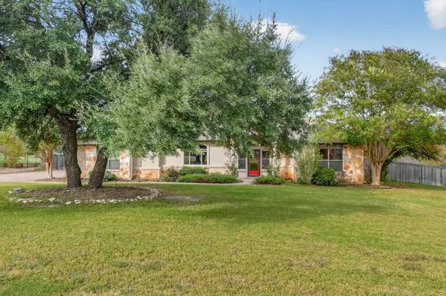 a view of a house with a big yard and large trees