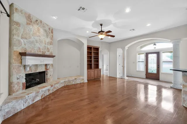 a view of an empty room with wooden floor fireplace and a window