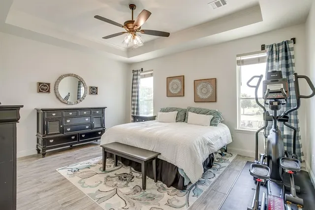 a bedroom with a bed a mirror on dresser and a chandelier