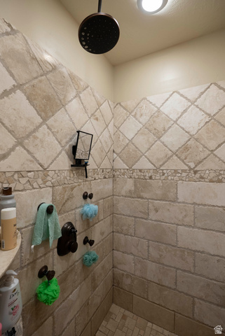 687 South 2080th Street East Springville, UT 84663 - Photo 25 of 149 Shower enclosure featuring natural stone-look tile in a diamond pattern, a bronze-finish rainfall showerhead, and a mosaic tile accent band