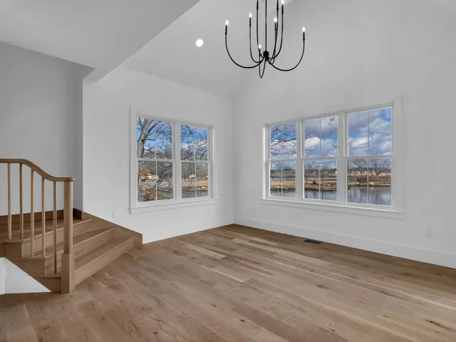 a view of an empty room with glass door and wooden floor