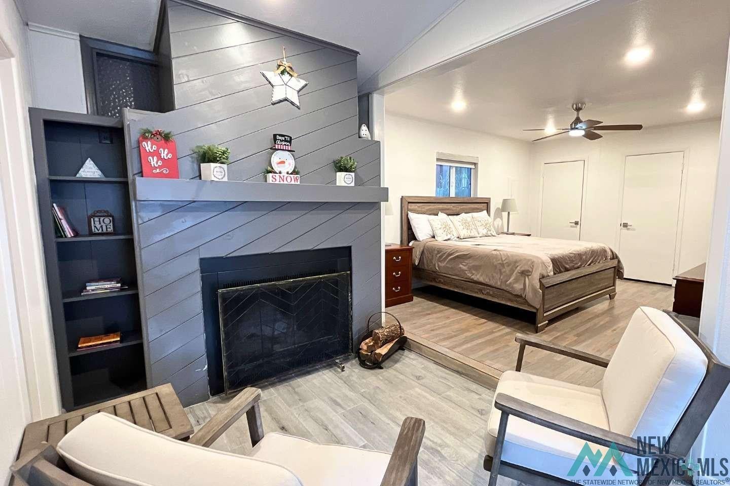 241 Junction Road Ruidoso, NM 88345 - Photo 15 of 44 Bedroom featuring light wood-type flooring, a fireplace, ceiling fan, multiple closets, and wooden walls