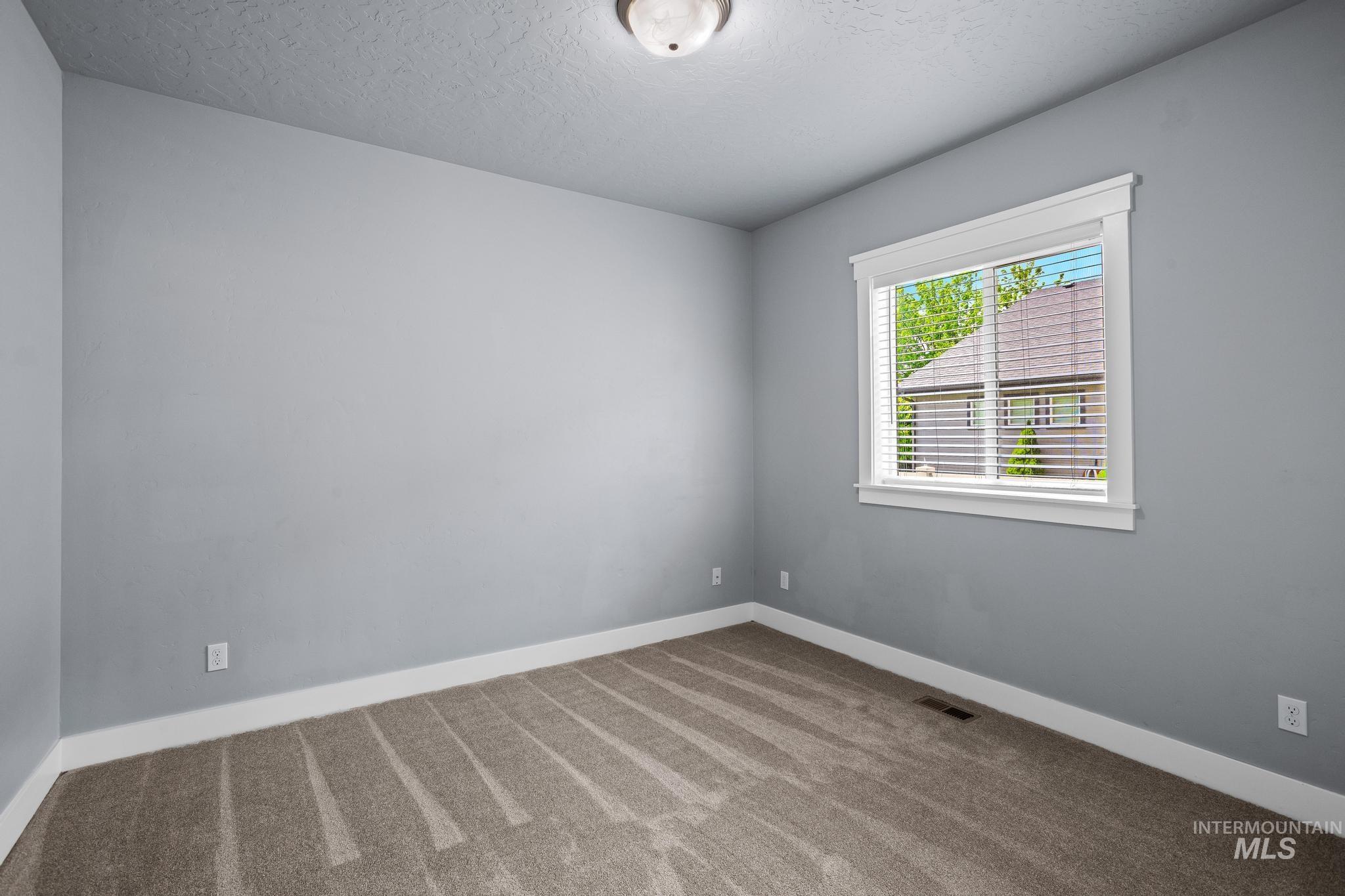 2681 East Rhyolite Court Nampa, ID 83686 - Photo 37 of 48 Neutral gray wall paint, textured ceiling, brown carpeting, white baseboards, and a window with white blinds and trim