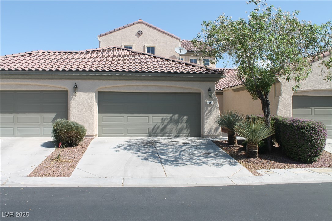 Mediterranean / spanish-style house featuring stucco siding, a tile roof, and driveway