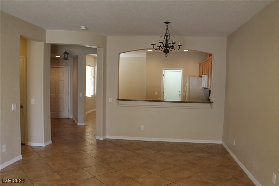 7352 Ravines Avenue Las Vegas, NV 89131 - Photo 14 of 93 Unfurnished room with light tile patterned floors and a chandelier