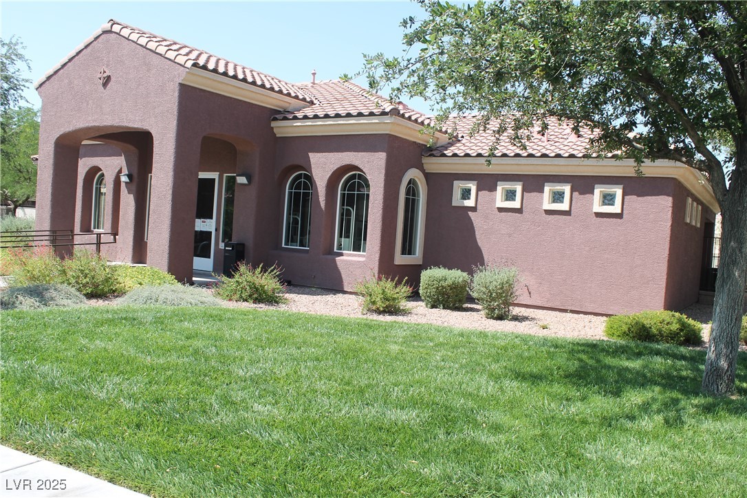 7352 Ravines Avenue Las Vegas, NV 89131 - Photo 20 of 93 View of home's exterior featuring a yard, stucco siding, and a tile roof