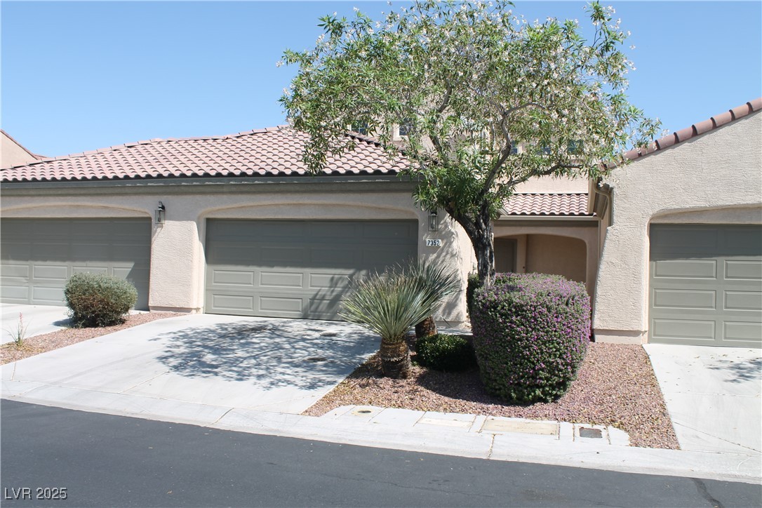7352 Ravines Avenue Las Vegas, NV 89131 - Photo 2 of 93 Mediterranean / spanish-style house with stucco siding, a tile roof, and a garage