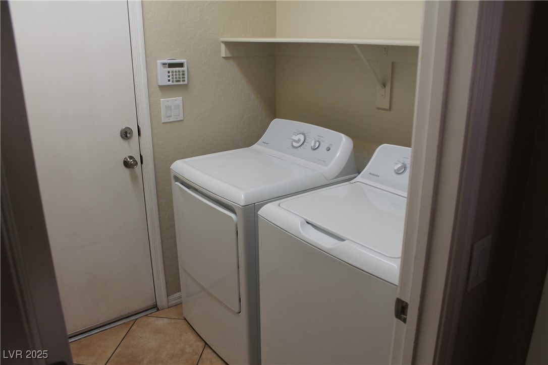 7352 Ravines Avenue Las Vegas, NV 89131 - Photo 29 of 93 Laundry room featuring light tile patterned floors, washing machine and clothes dryer, and a textured wall