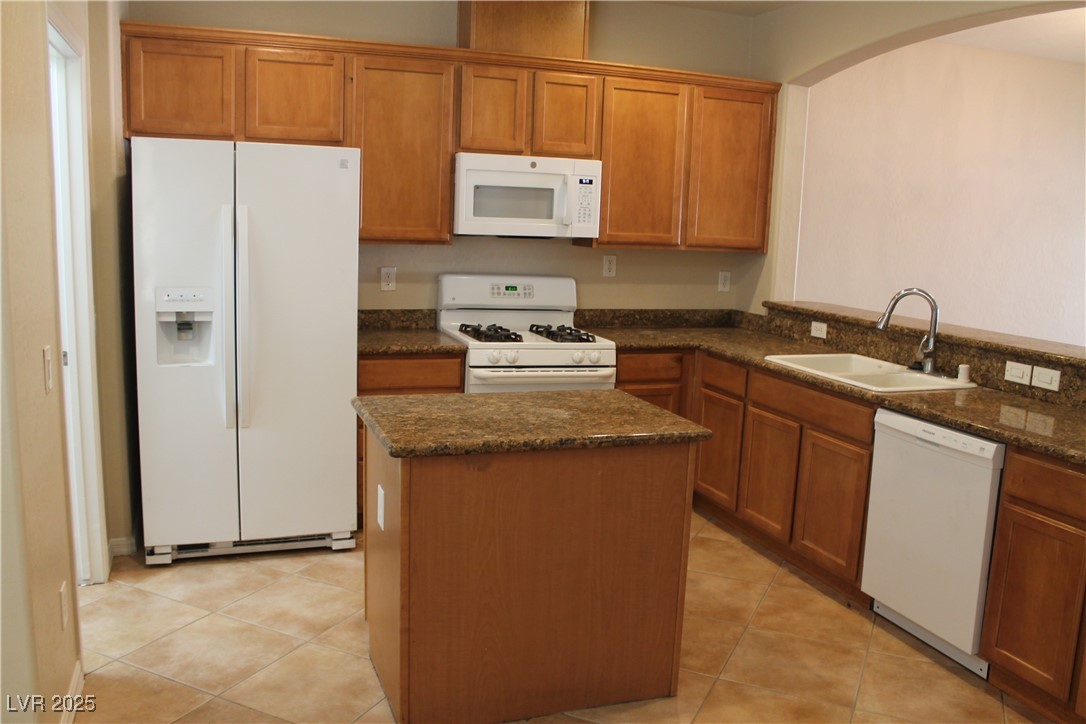 7352 Ravines Avenue Las Vegas, NV 89131 - Photo 41 of 93 Kitchen featuring white appliances, brown cabinets, light tile patterned floors, and a kitchen island