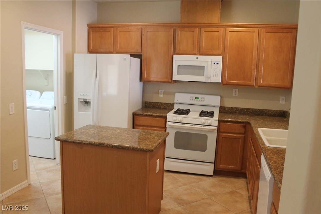 7352 Ravines Avenue Las Vegas, NV 89131 - Photo 43 of 93 Kitchen featuring white appliances, a kitchen island, brown cabinets, and light tile patterned floors
