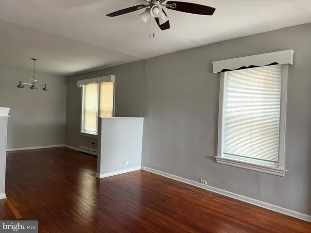 an empty room with wooden floor cabinet and windows