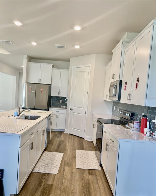 4307 Pullet Court Lakewood Ranch, FL 34211 - Photo 2 of 16 a kitchen that has a lot of cabinets in it and wooden floors