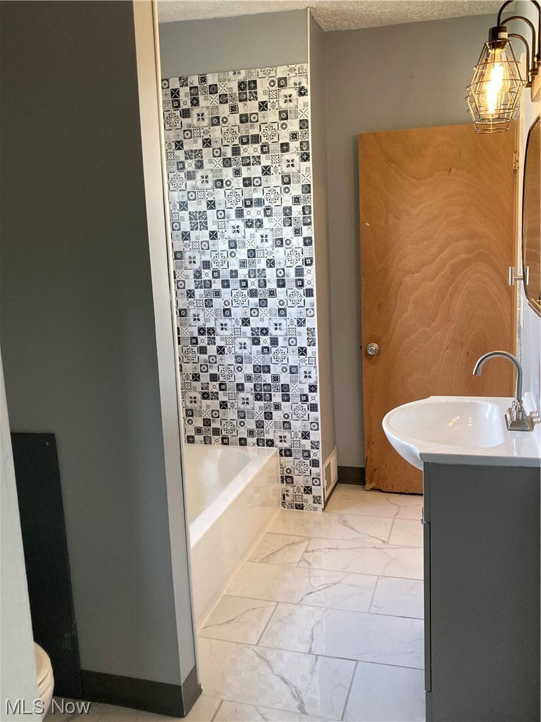 183 East Wilbeth Road Akron, OH 44301 - Photo 17 of 26 Bathroom featuring a textured ceiling, vanity, a washtub, and light tile floors