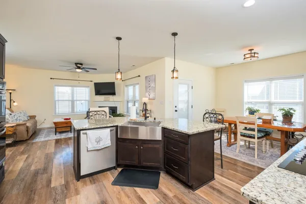 a kitchen with stainless steel appliances kitchen island granite countertop a sink a stove and a wooden floors