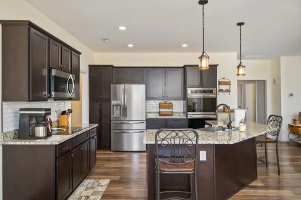 a kitchen with stainless steel appliances granite countertop a refrigerator a stove a sink dishwasher a oven with a dining table and chairs