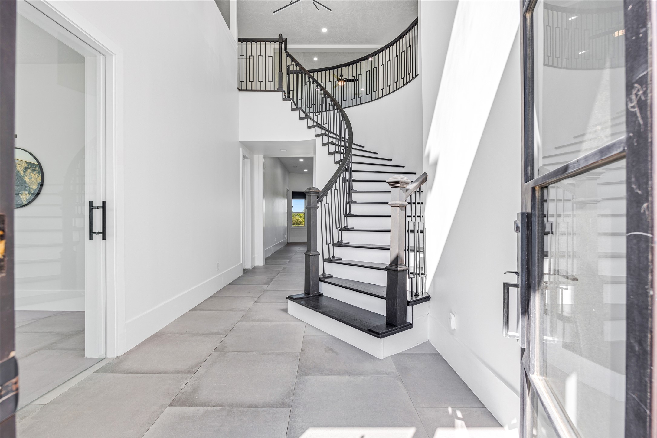 15015 House Road Cypress, TX 77433 - Photo 11 of 50 This elegant entryway features a grand, curved staircase with modern railings, high ceilings, and large tile flooring, providing a bright and welcoming atmosphere.