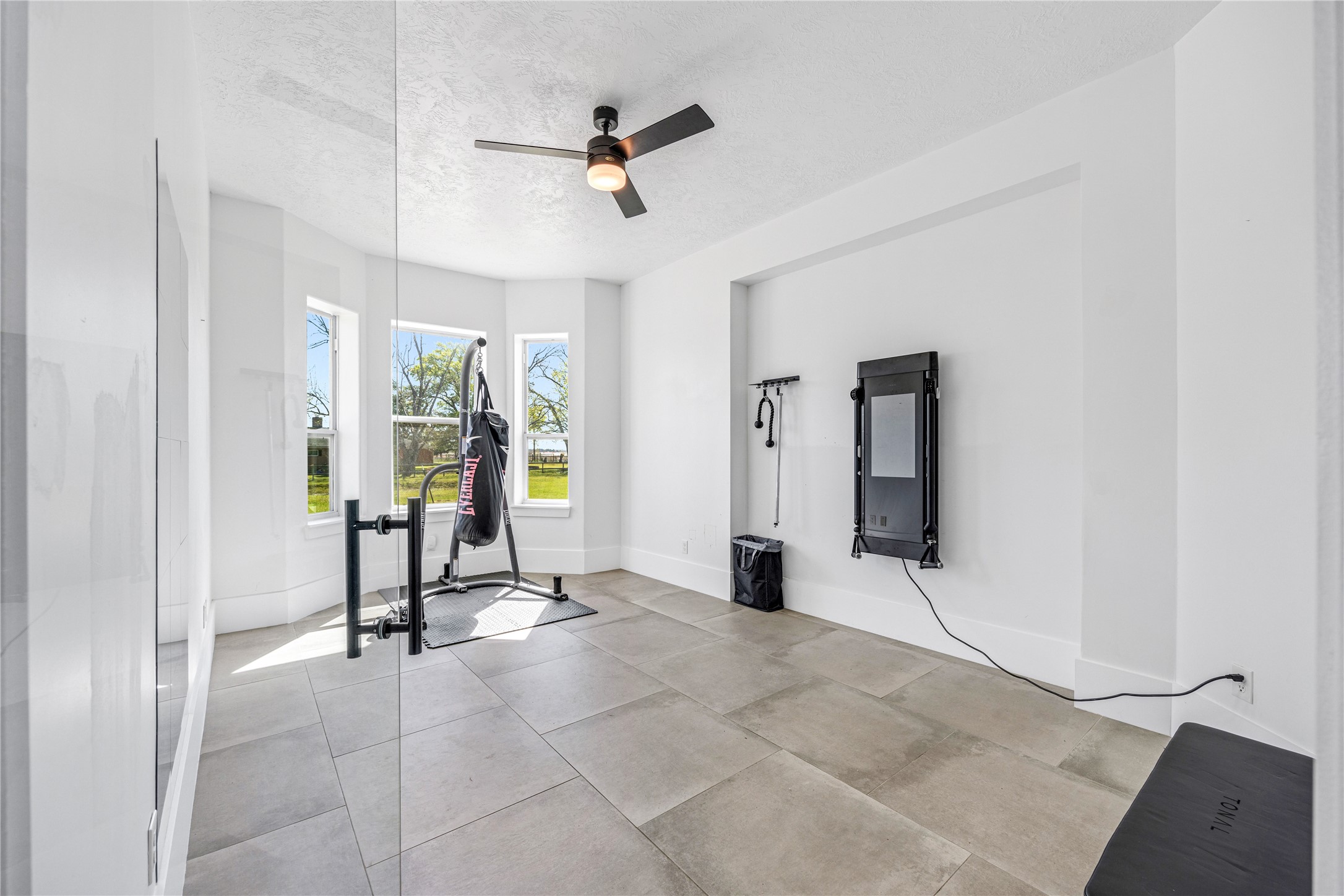 15015 House Road Cypress, TX 77433 - Photo 22 of 50 This bright, modern home gym features large windows, a ceiling fan, and fitness equipment, creating an inviting space for workouts.