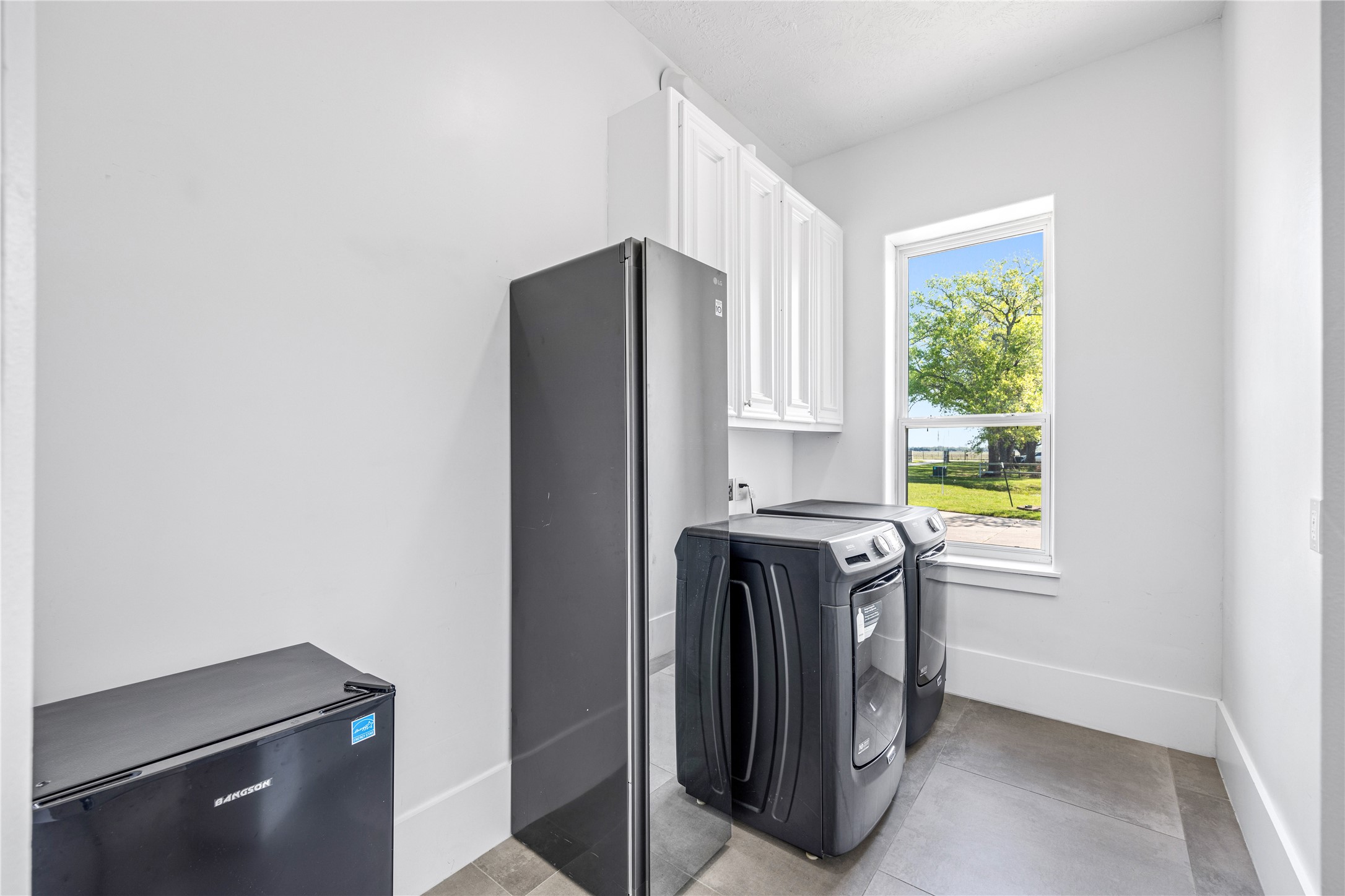 15015 House Road Cypress, TX 77433 - Photo 23 of 50 This bright laundry room features modern appliances, ample cabinetry, and a window with a scenic outdoor view, creating a functional and pleasant workspace.