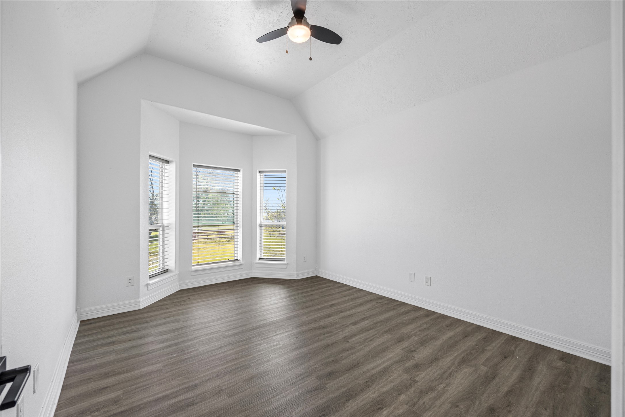 15015 House Road Cypress, TX 77433 - Photo 34 of 50 This room features a vaulted ceiling with a modern ceiling fan, large bay windows for natural light, and elegant wood flooring, creating a bright and welcoming space.