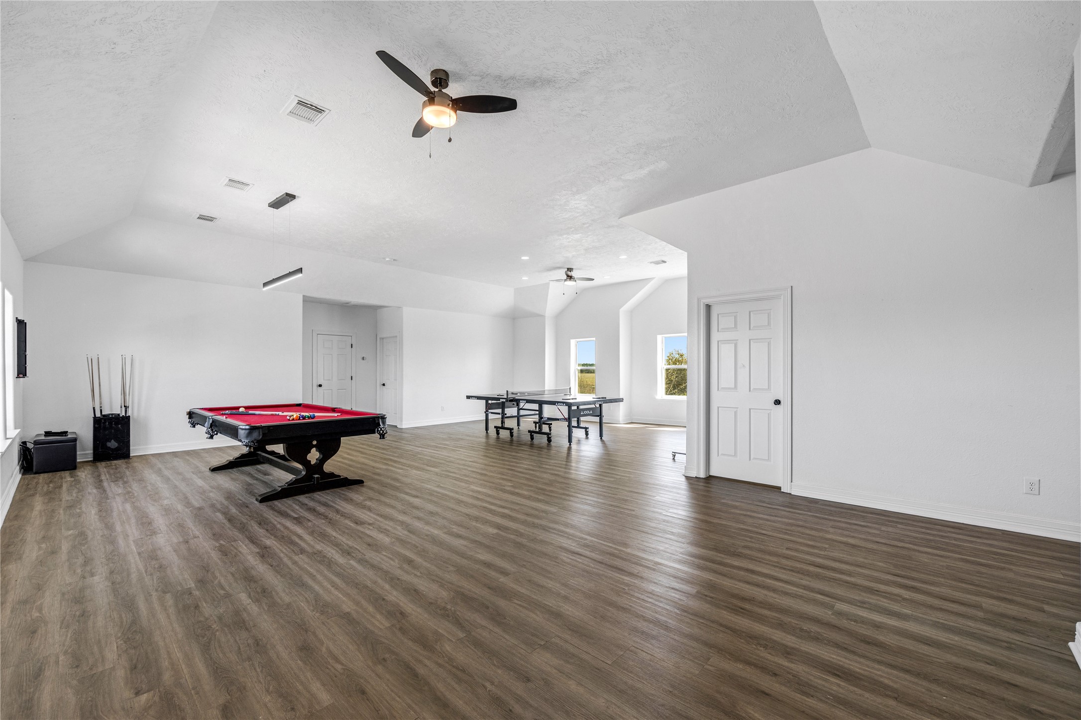 15015 House Road Cypress, TX 77433 - Photo 37 of 50 Spacious game room with wood flooring, featuring pool and ping pong tables. Bright with natural light from multiple windows, it includes ceiling fans for comfort. Ideal for entertainment and leisure.