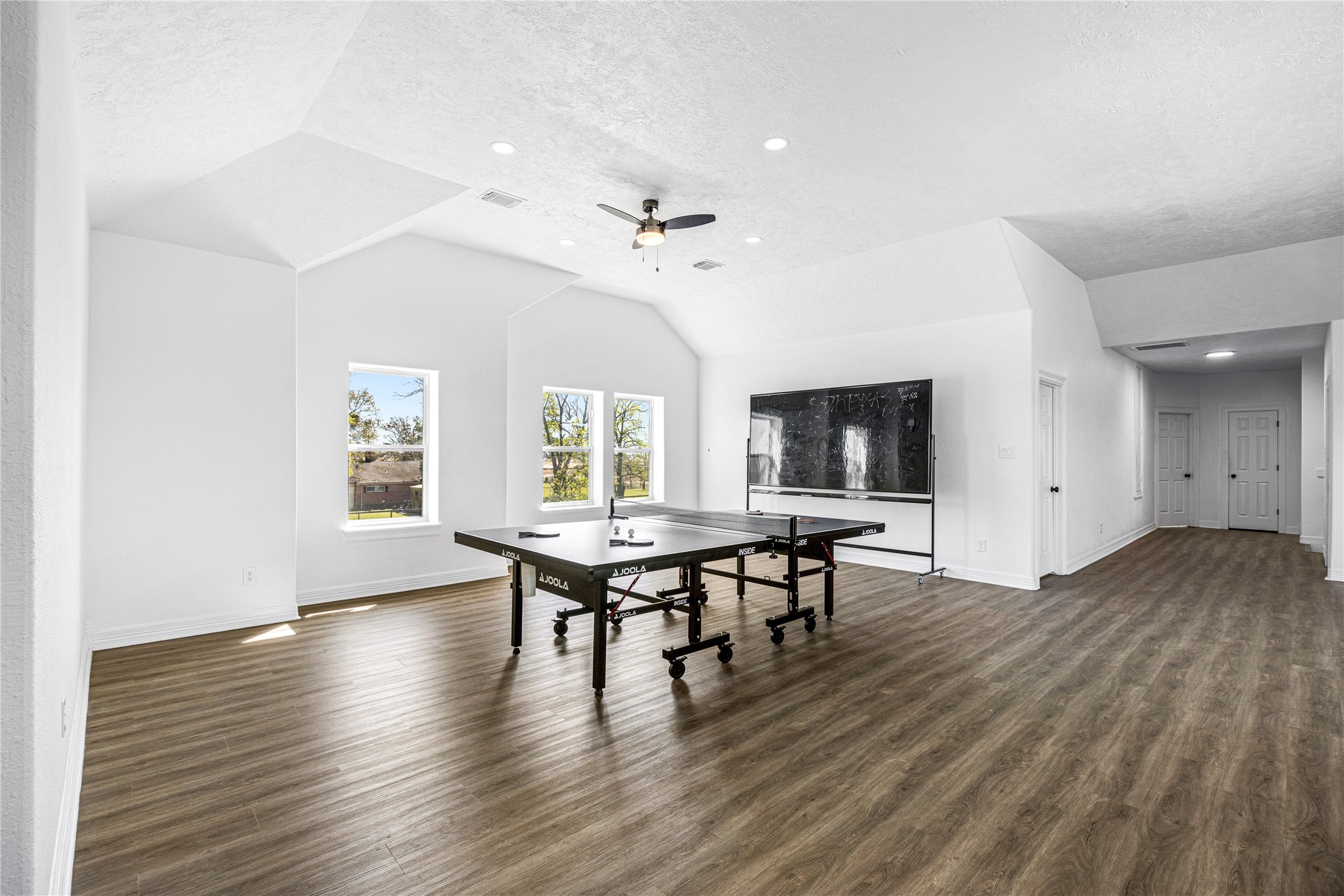 15015 House Road Cypress, TX 77433 - Photo 38 of 50 This spacious, bright game room features a ping pong table, wood-style flooring, and ample natural light from multiple windows, making it perfect for entertainment and relaxation.