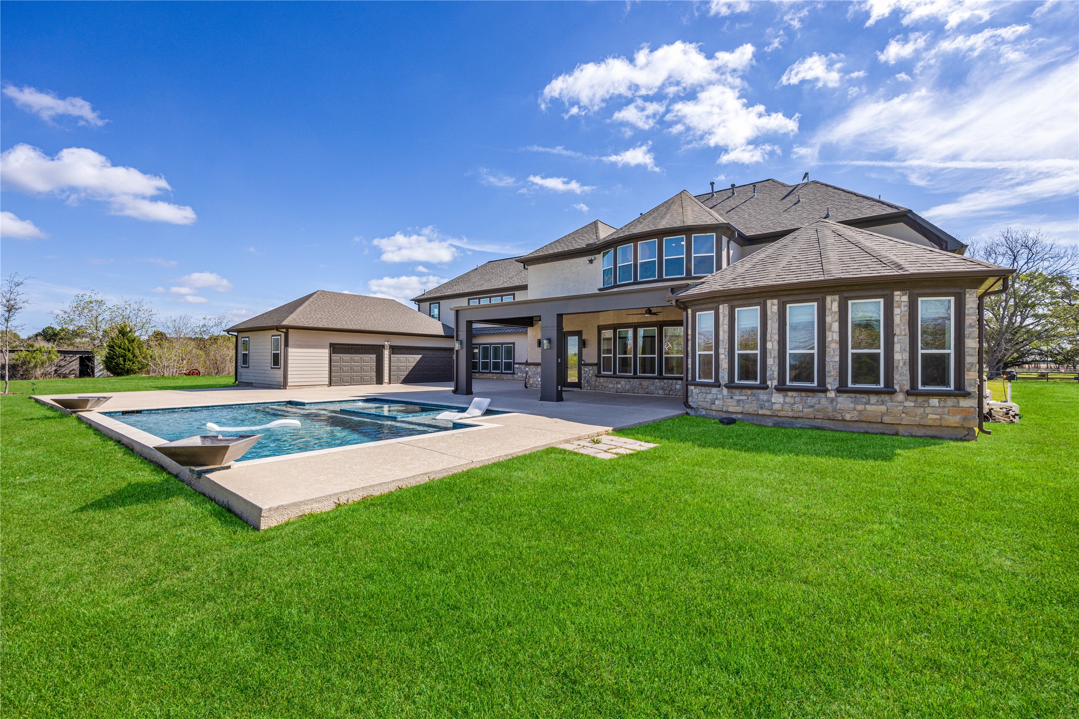 15015 House Road Cypress, TX 77433 - Photo 4 of 50 This stunning home features a spacious backyard with a sleek swimming pool, expansive lawn, and a modern exterior design. Large windows provide ample natural light, and the property includes a detached garage for convenience. Perfect for outdoor entertaining and relaxation.