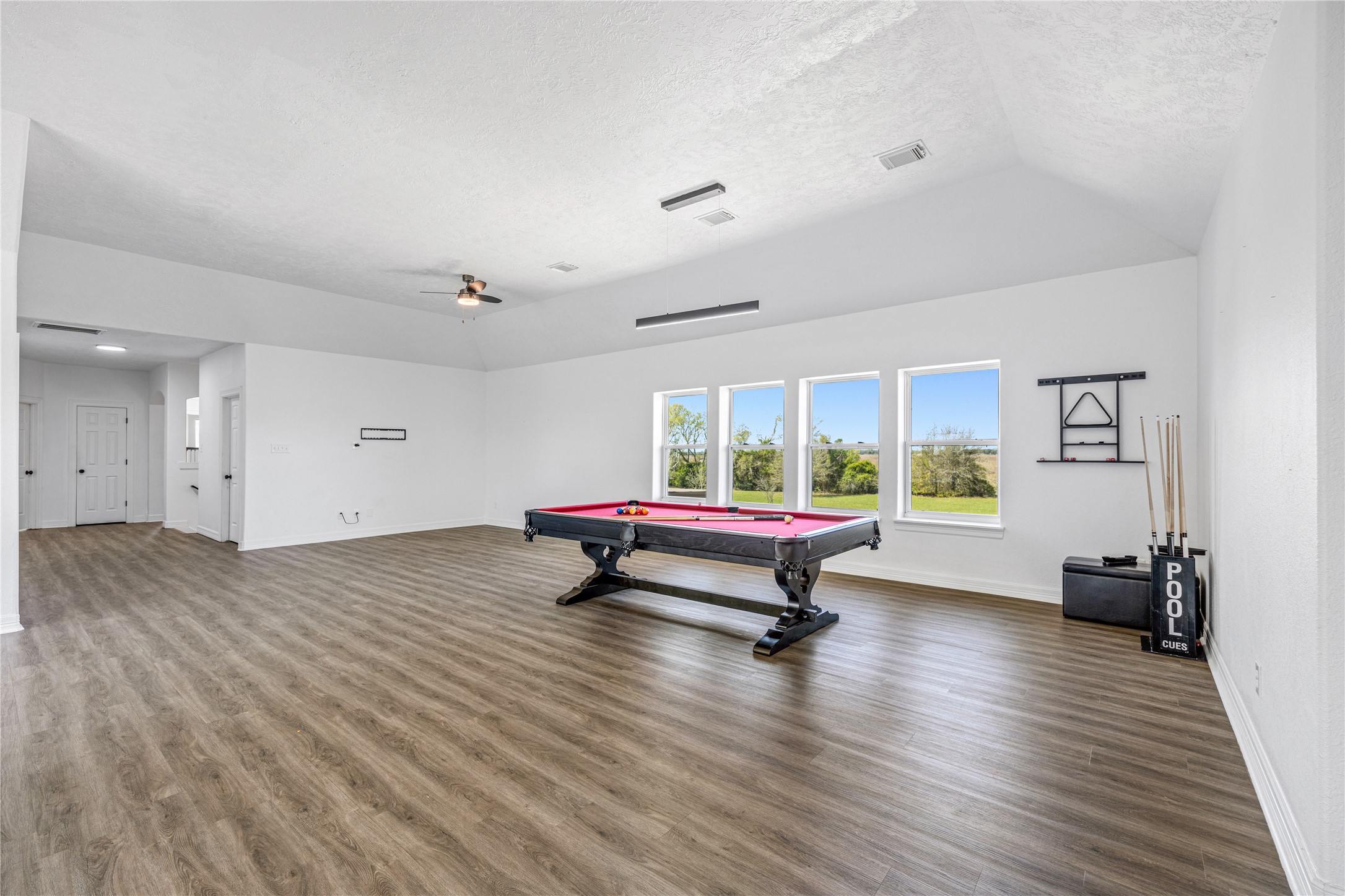 15015 House Road Cypress, TX 77433 - Photo 39 of 50 Spacious game room with modern wood flooring, featuring a pool table and ample natural light from large windows overlooking a scenic view. Ideal for entertaining or relaxation.