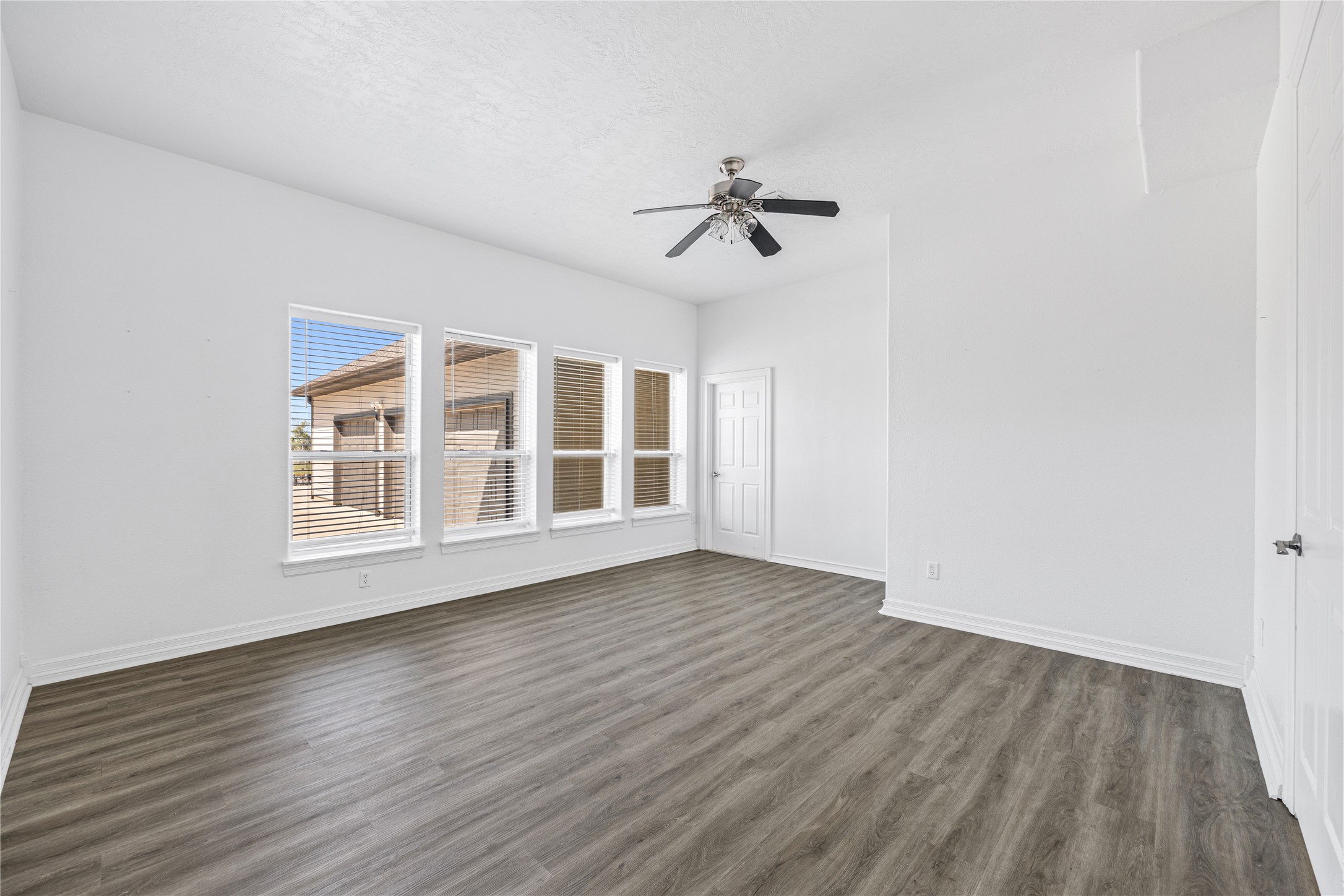 15015 House Road Cypress, TX 77433 - Photo 47 of 50 Bright, spacious room with large windows, modern wood-style flooring, and a ceiling fan. Fresh white walls create a clean and inviting atmosphere.